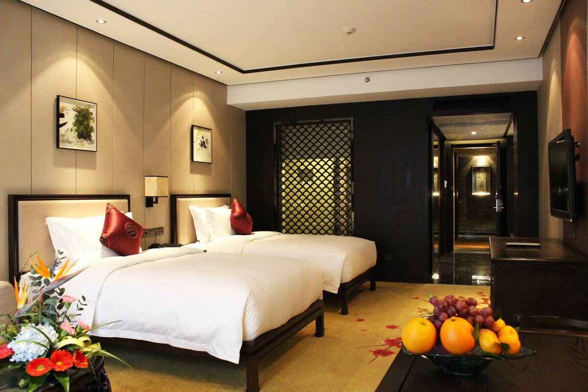 Une chambre d’hôtel avec deux lits, une table à manger avec des fruits et un téléviseur.