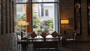A lobby with a seating area, a view of an outdoor garden, and a large window. - Xiang Yun Sha Garden Hotel (Foshan)