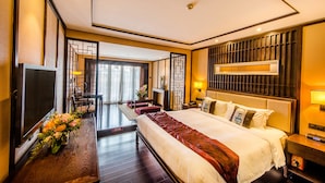 A hotel room with a large bed, a TV, a desk with a lamp, and a view of the outside. - Xiang Yun Sha Garden Hotel (Foshan)