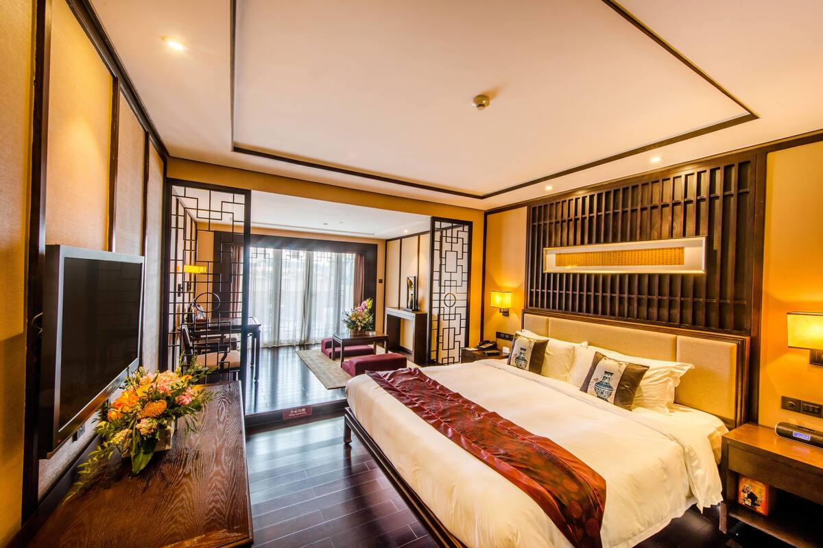 Une chambre d’hôtel avec un grand lit, une télévision, un bureau avec une lampe et une vue sur l’extérieur.