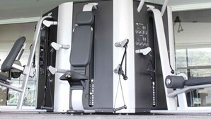 Un gimnasio con diversas máquinas de ejercicio, incluyendo una máquina de press de pecho multidireccional y una máquina para extensiones de piernas.