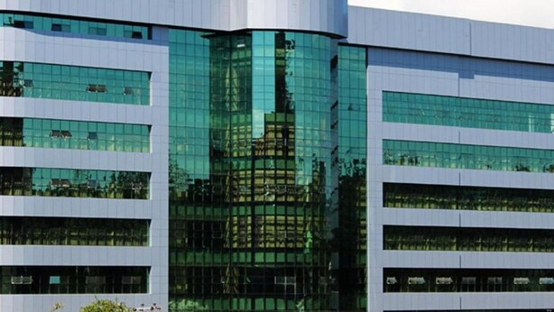 Un edificio moderno de varios pisos con amplias ventanas de vidrio que reflejan el entorno.