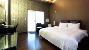 A hotel room with a large bed, a desk with a chair, a radiator, and a window. - Cyuan Tang Hot Spring Hotel (Jiaoxi)