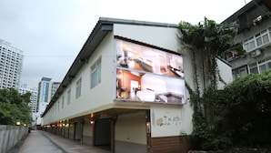 A two-story building with a ground floor that appears to be a commercial space with closed shutters, and a residential upper floor with visible windows and a balcony. - Cyuan Tang Hot Spring Hotel (Jiaoxi)