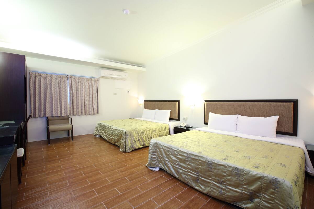 A hotel room with two beds, a desk, and a chair.