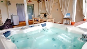 A room with a large bathtub, a fan, a table, and a window with curtains. - Villa Amidala - Waingapu (Waingapu)