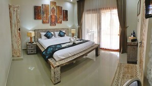 A spacious hotel room with a large bed, a nightstand, a bedside table, a wardrobe, and a window with curtains. - Villa Amidala - Waingapu (Waingapu)