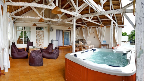 A spacious indoor area with a hot tub, wooden flooring, and a dining area with chairs and a table. - Villa Amidala - Waingapu (Waingapu)