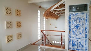A staircase with a wooden handrail, a blue door with a star design, and decorative wall panels. - Villa Amidala - Waingapu (Waingapu)