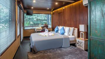 A modern hotel room with a large bed, a bedside table, a small cabinet, and a TV mounted on the wall.