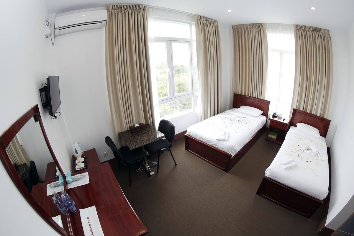 Una habitación de hotel con dos camas, un escritorio con silla, televisión y equipo de aire acondicionado.