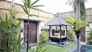 Un patio trasero con cerco de madera, un pequeño pabellón, piscina y varias plantas.