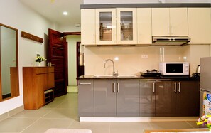 Una cocina moderna con microondas integrado, pileta de acero inoxidable y un mueble de madera.