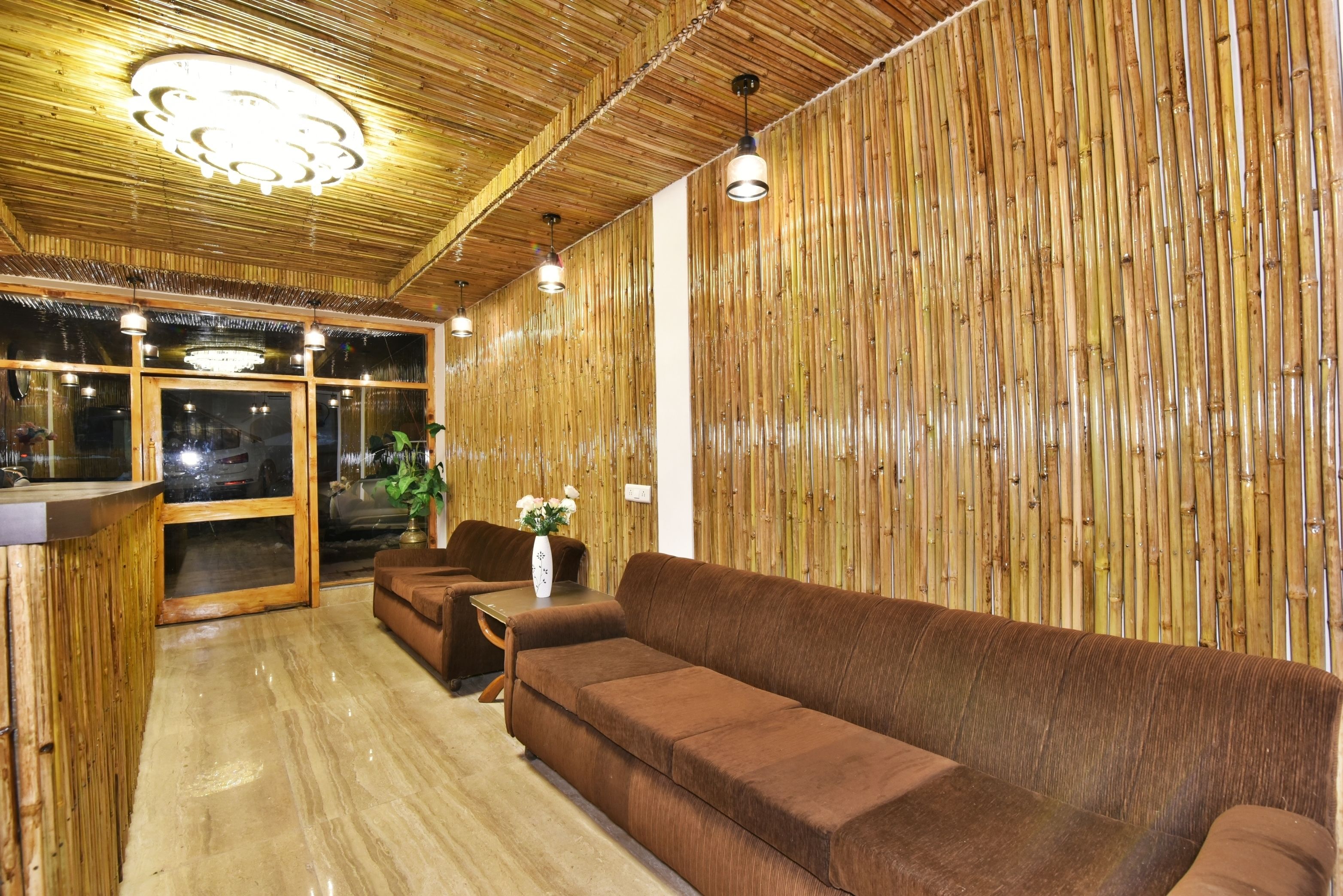 A modern interior with a wooden ceiling, a brown sofa, a wooden table with a vase, and a large window.