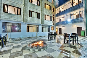 A courtyard with a fire pit, checkered flooring, and outdoor seating. - Kapoor Resort (Manali)