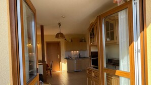 A kitchen with wooden cabinets, a dining area with a table and chairs, and a ceiling light fixture. - Vacation apartment 3 - Holiday home Karsten (Karlshagen)