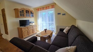 A living room with a sofa, a TV, wooden cabinets, and a dining table. - Vacation apartment 3 - Holiday home Karsten (Karlshagen)