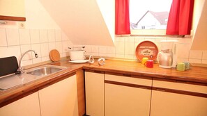 A kitchen with a sink, a coffee maker, and a window with red curtains. - Art City-Studio Kassel 5 - ART City-Studio Kassel 5 (Niestetal)