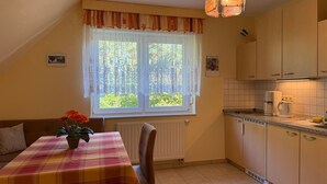 Pieni keittiö, jossa on ruokapöytä, patteri ja ikkuna, jossa on verhot.