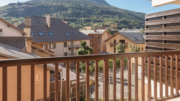 A balcony with a view of a mountain and residential buildings.