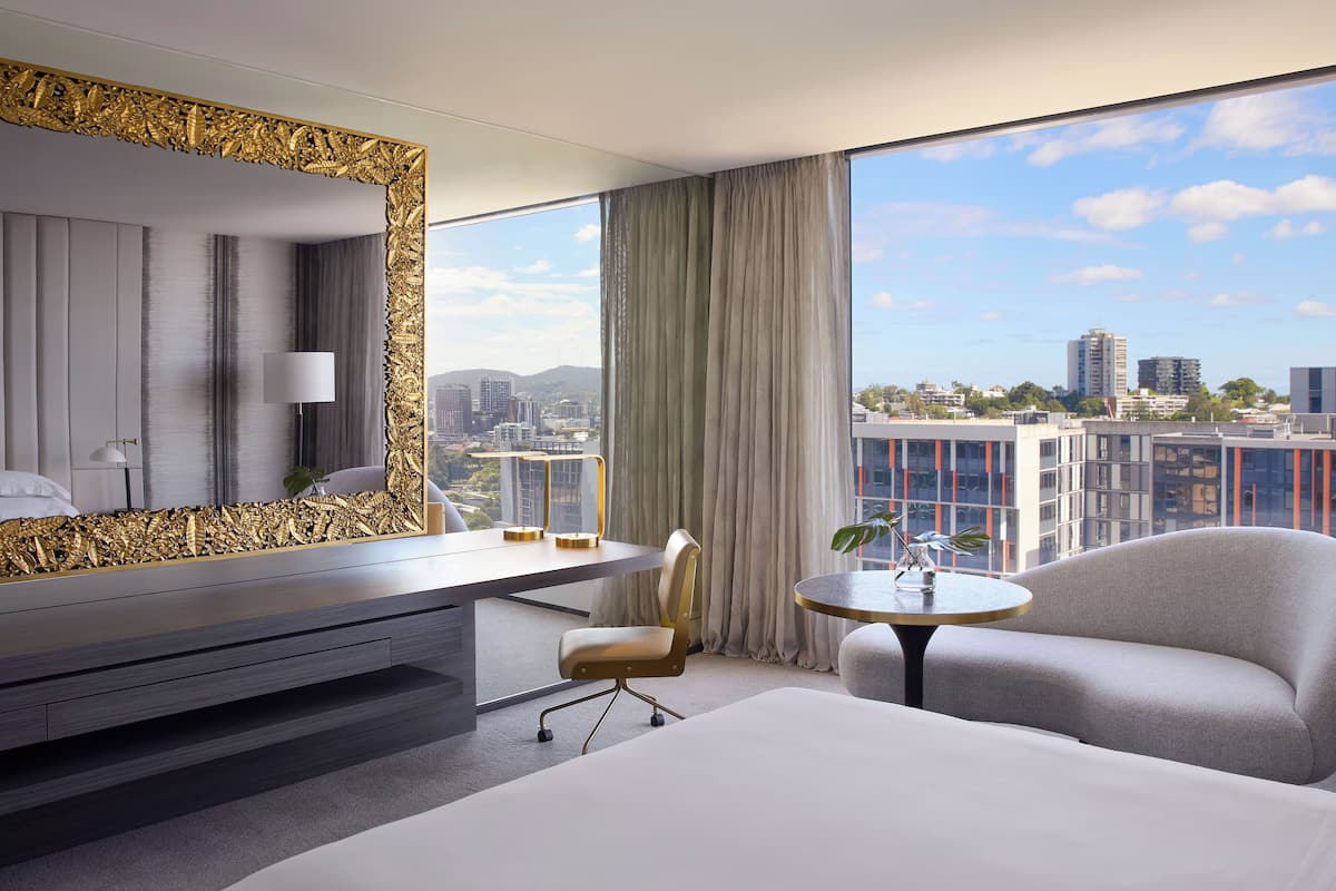 Een moderne hotelkamer met een groot bed, een bureau, een stoel en een ronde tafel.