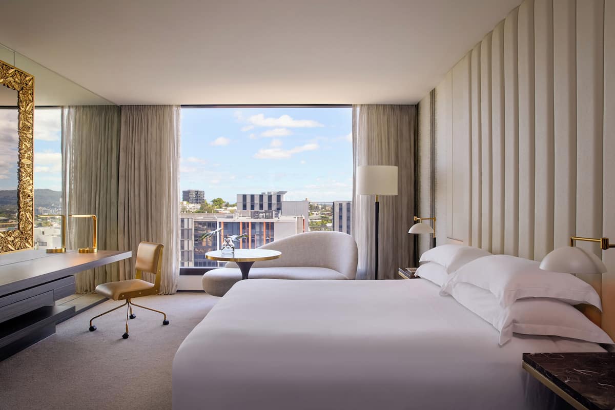 Een hotelkamer met een groot bed, een bureau, een stoel en uitzicht op de stad.