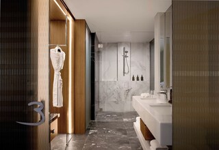 A modern bathroom with a shower, a vanity with a mirror, and a robe hanging on a door.