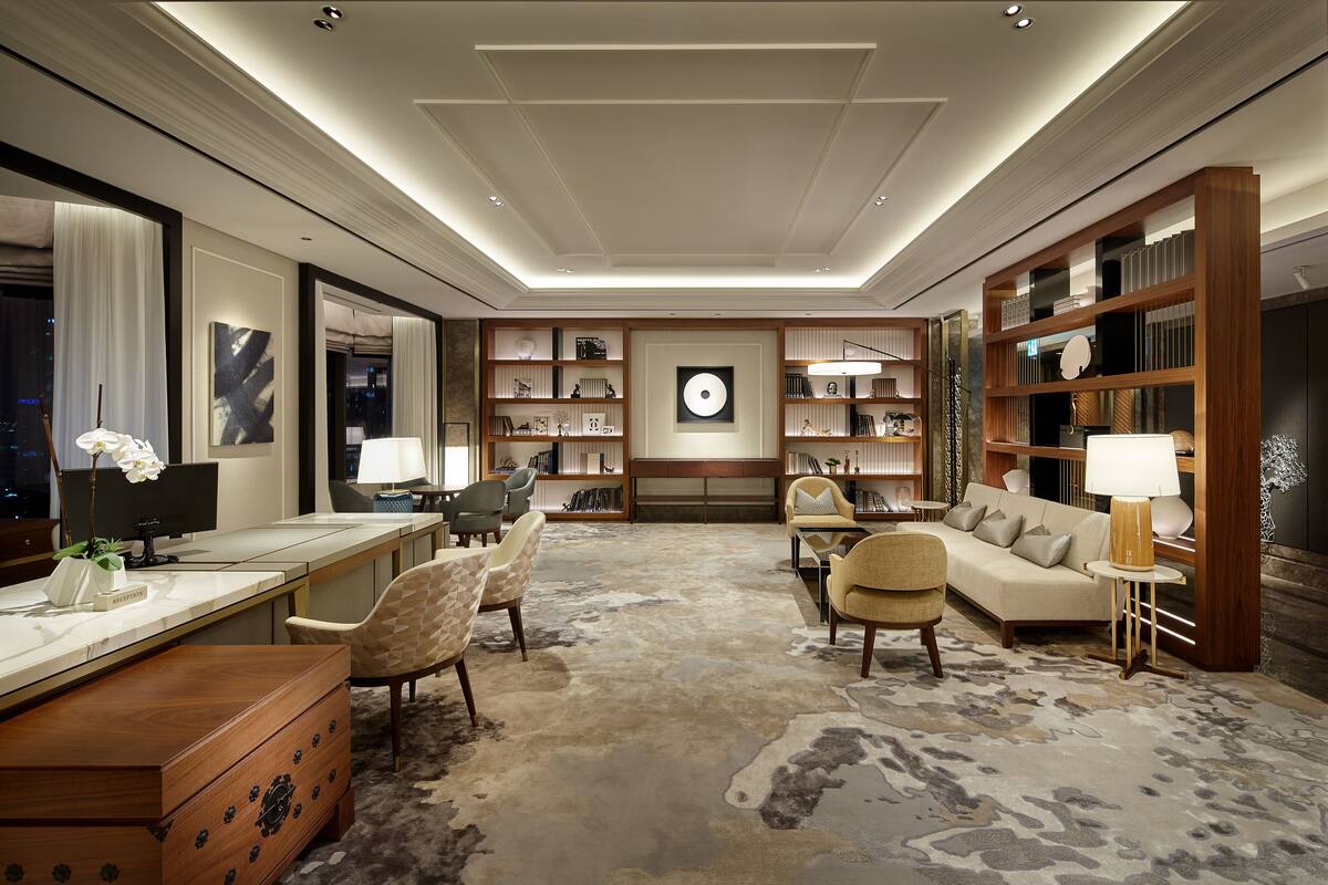 Ein geräumiges Wohnzimmer mit einer großen Couch, einem Schreibtisch und einem Bücherregal.