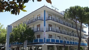 Un hotel de varios pisos con balcones, una tienda en la planta baja y una zona peatonal.