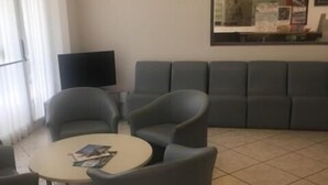 Un vestíbulo de hotel con una zona de estar, una mesa redonda y un televisor de pantalla plana.