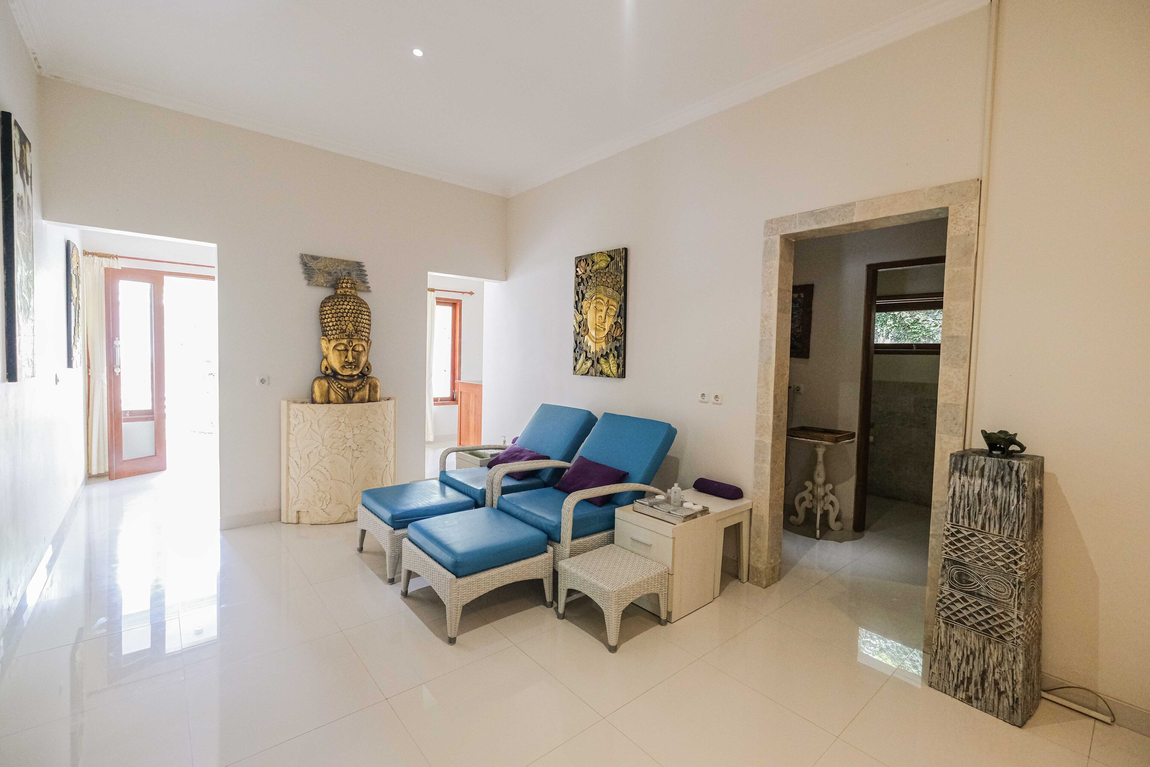 Una habitación amplia con un amplio sofá, una mesita pequeña y una estatua decorativa de Buda.