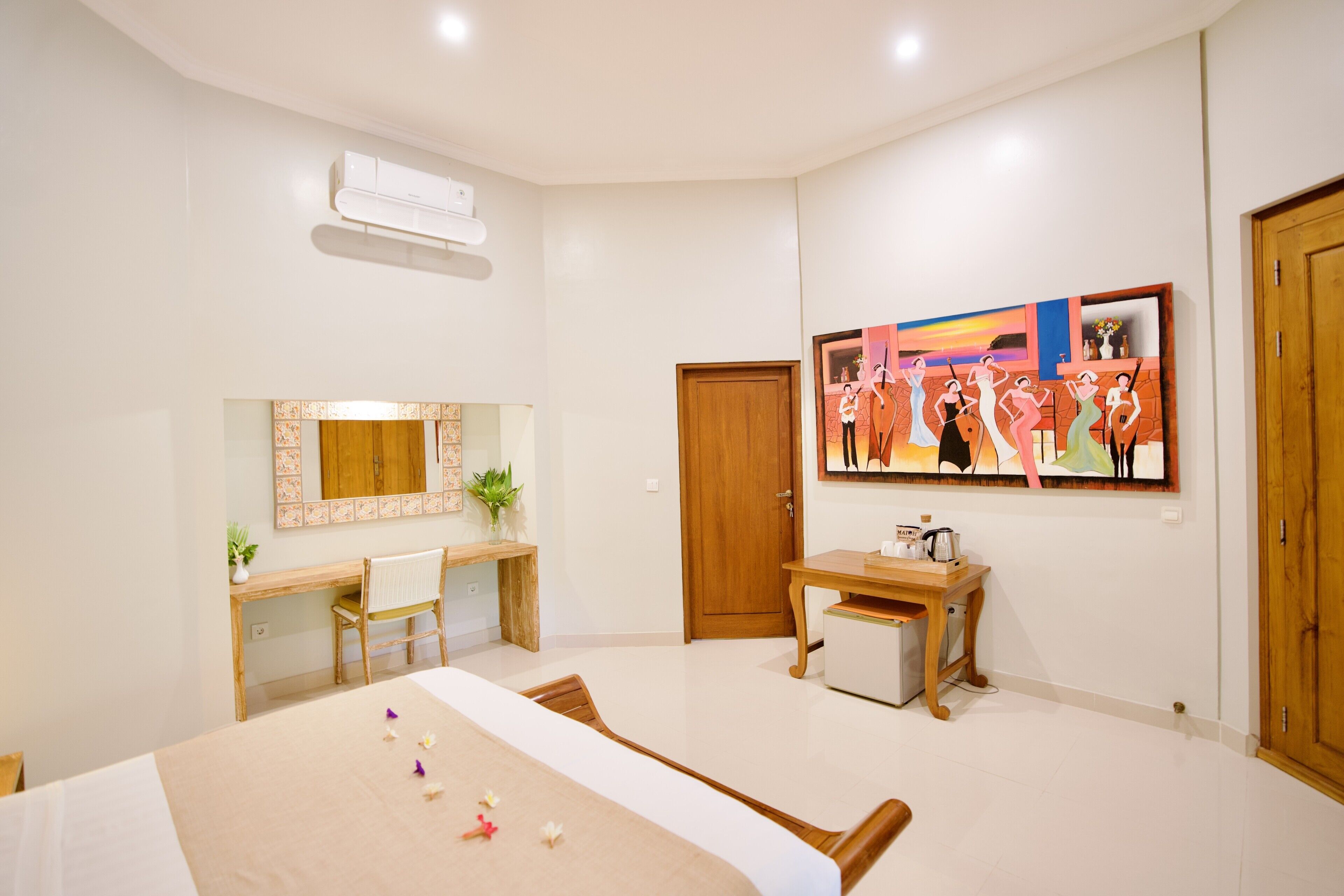 A bedroom with a bed, a desk, a chair, a wooden wardrobe, a mirror, and a painting on the wall.