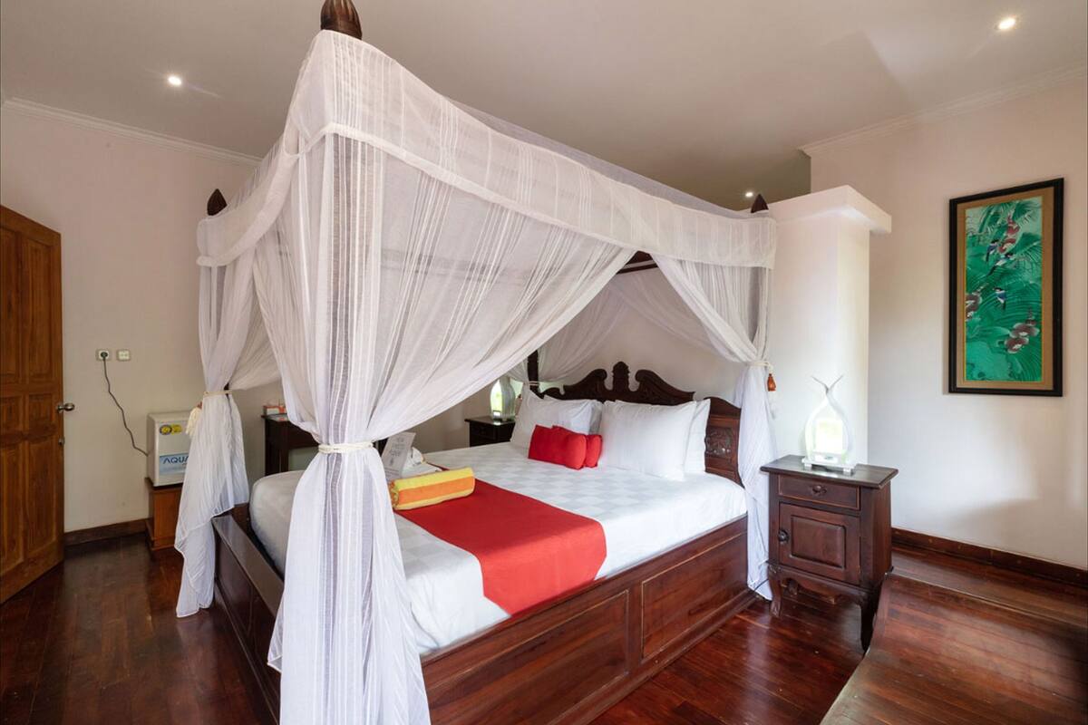 A four-poster canopy bed with a wooden headboard, a bedside table, and a nightstand.