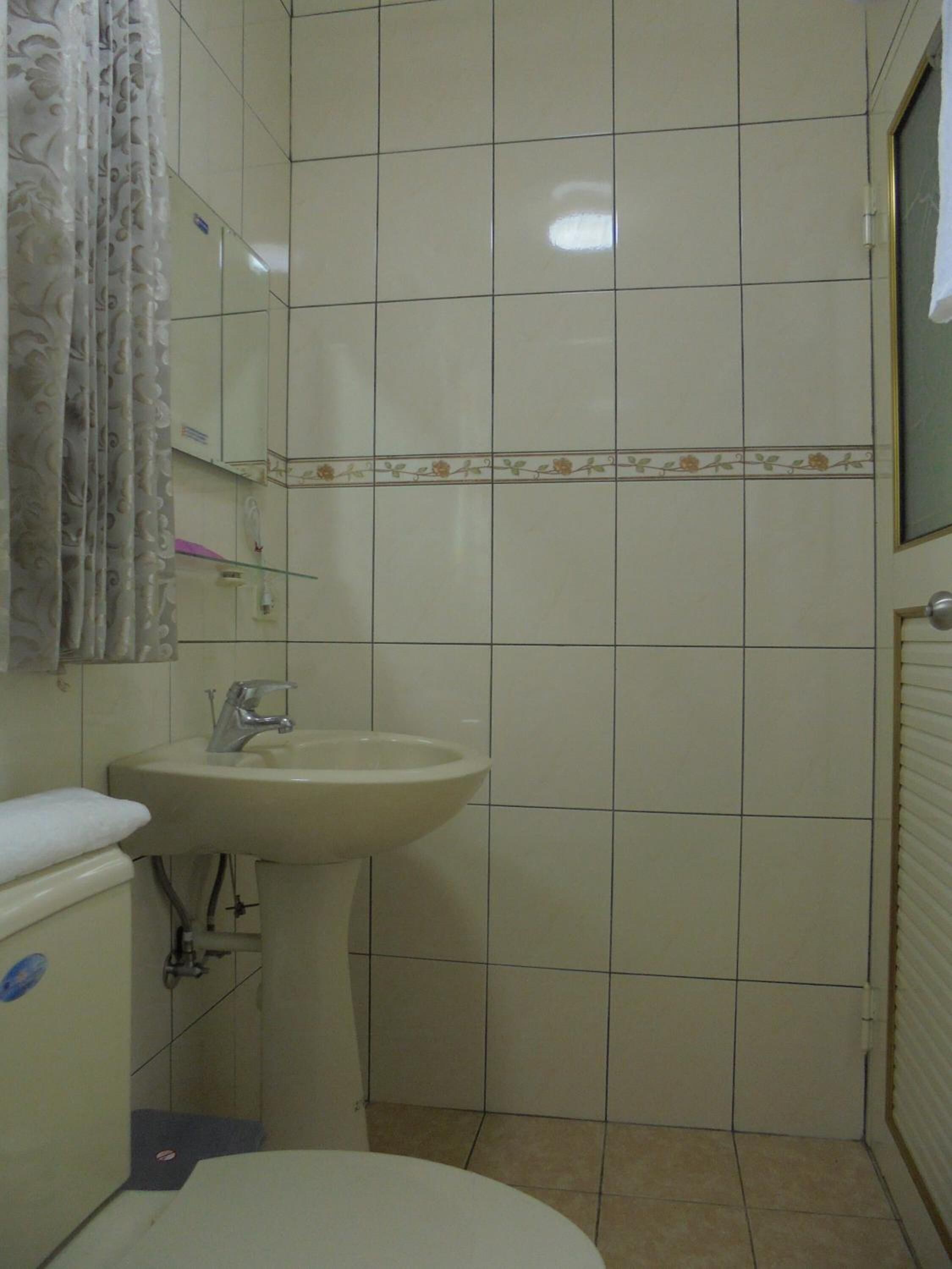 A small bathroom with a toilet, sink, and shower.