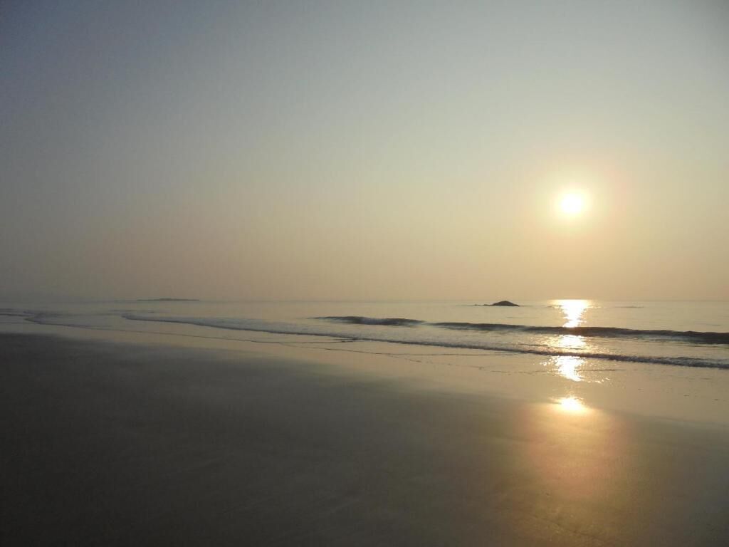 Una playa con el sol reflejado en el agua.