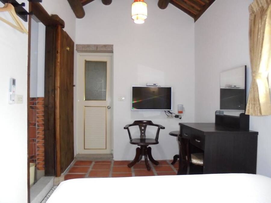 A room with a bed, a desk, a chair, a television, and a door.