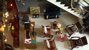 Une pièce spacieuse avec un bureau en bois, plusieurs chaises, un escalier et un tableau accroché au mur.