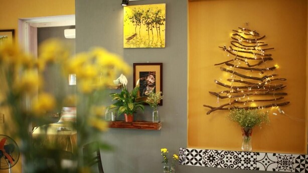 Une pièce avec une œuvre d’art accrochée au mur, une petite table sur laquelle est posé un vase, et une chaise.
