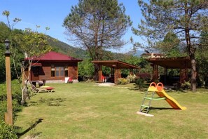 A house with a red roof, a wooden deck, and a slide in the yard. - Pinar Kir Evi (Arhavi)