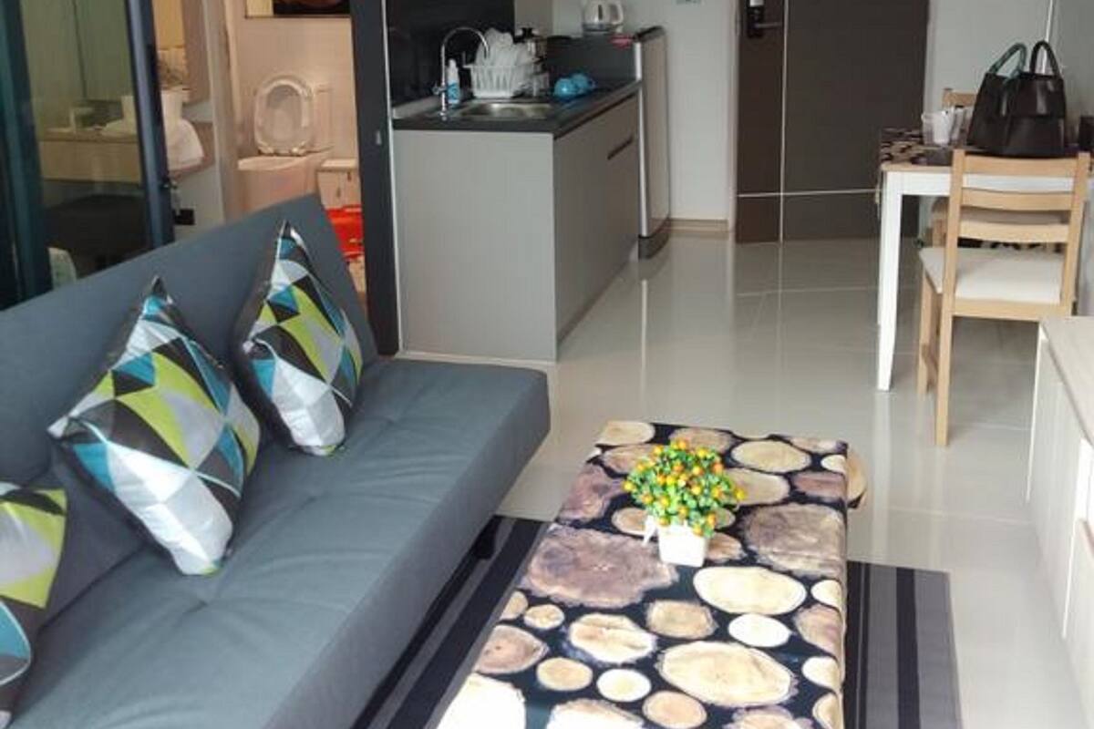 A modern living room with a sofa, a coffee table, and a view into the kitchen.