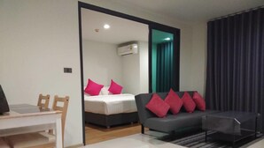 A modern hotel room with a bed, a sofa, a dining table, and a chair. - Apartment at Punnawithi BTS (Bangkok)