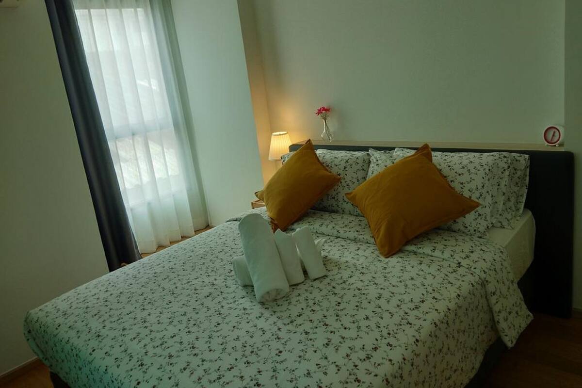 A hotel room with a bed, a nightstand, a lamp, and a window with curtains.