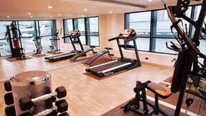 A gym with treadmills, weight machines, and a rowing machine. - Apartment at Punnawithi BTS (Bangkok)