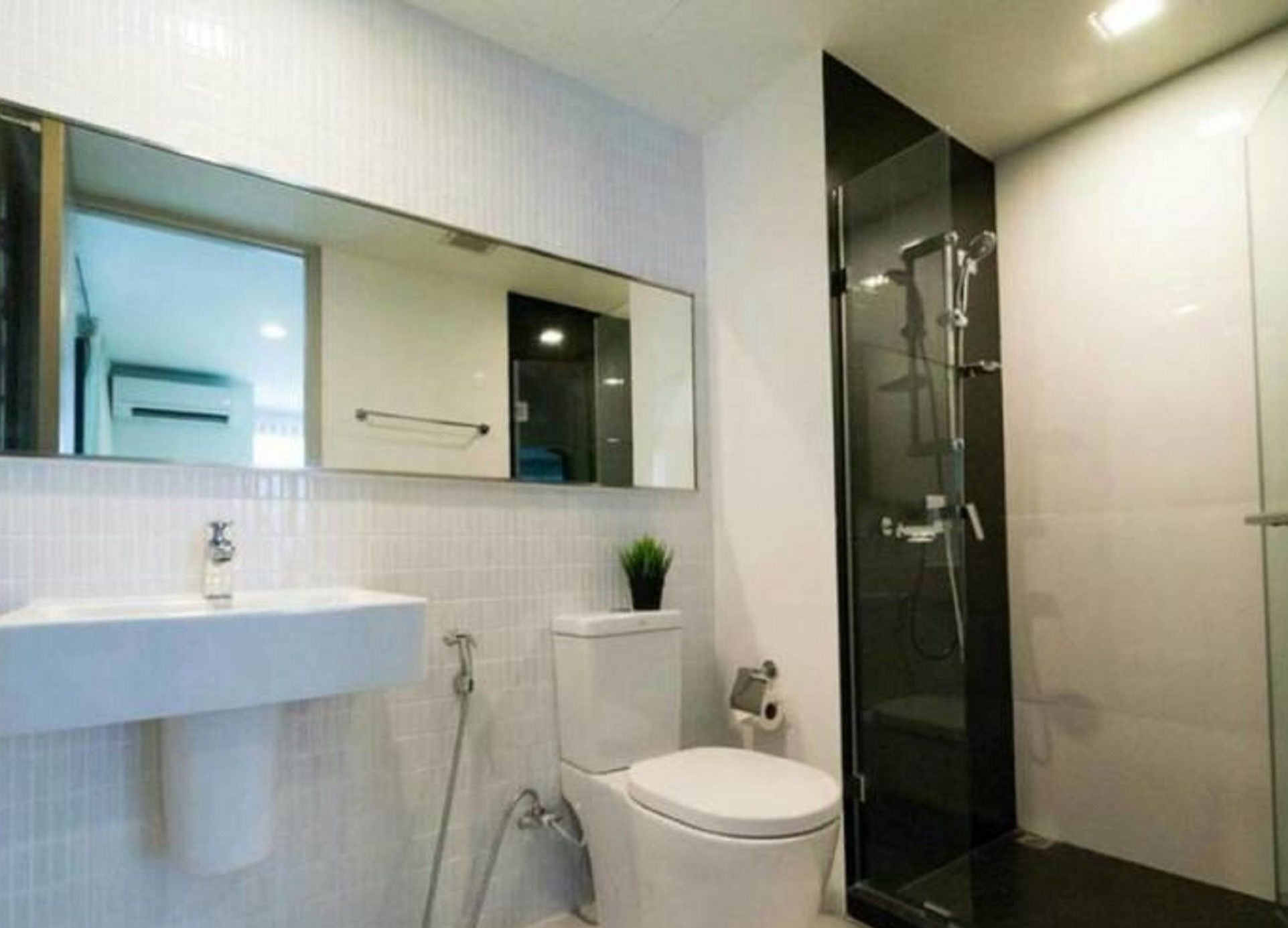 A modern bathroom with a white sink, toilet, and a glass-enclosed shower.