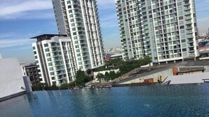 A swimming pool with a tiled edge, surrounded by high-rise buildings. - Apartment at Punnawithi BTS (Bangkok)