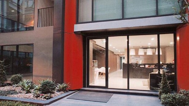 A modern building with a glass entrance, a visible kitchen area, and a small garden with plants. - Apartment at Punnawithi BTS (Bangkok)
