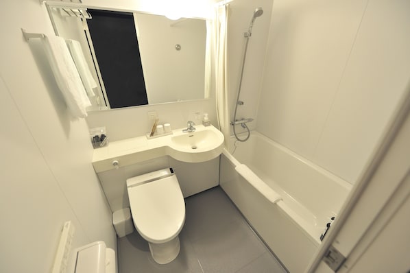 Un baño pequeño con inodoro, lavamanos y ducha.