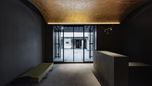 A reception area with a bench, a reception desk, and a view through a glass door to the outside. - FUGASTAY Shijo Omiya (Kyoto)