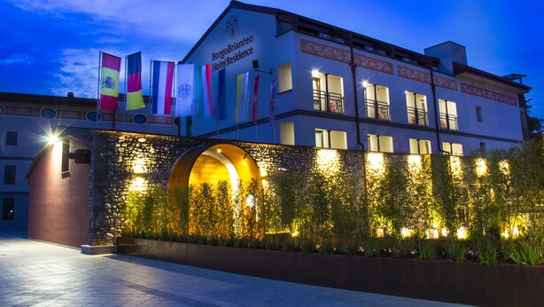 A hotel with a stone facade, multiple flags, and an arched entrance.