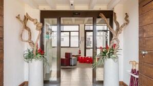 A hotel lobby with a modern design, featuring a reception desk, seating area, and decorative wooden elements.